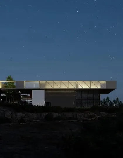 A night view of the Dhruva space technology campus. The lighting highlights the building's form as it floats above the rocks, creating a dramatic and futuristic presence in the landscape while respecting the natural contours of the site.