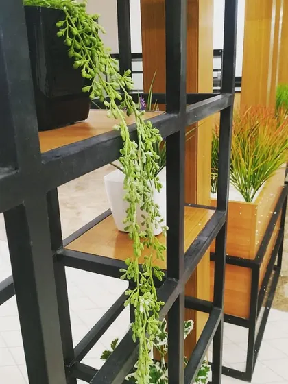 A detail shot of the plant-filled divider. The trailing artificial string of pearls plant adds softness and a sense of movement, contrasting nicely with the rigid structure of the black metal grid.