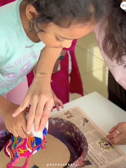 A participant carefully tilts her canvas to guide the flow of paint, an essential step in creating the final look of a fluid art piece.