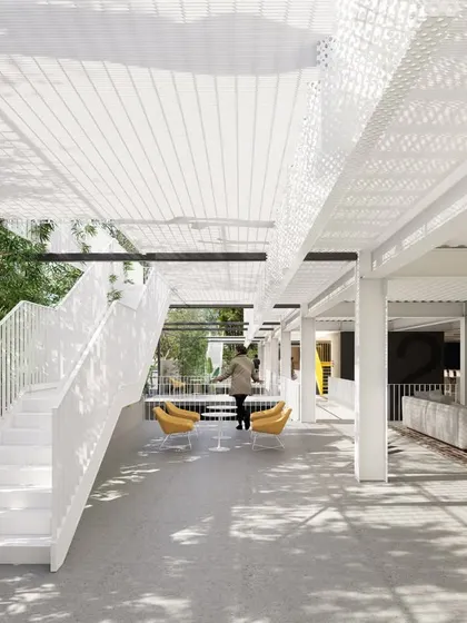 The shared amenity spaces in our co-living project are designed to be open and connected to nature. This view shows a lounge area under a perforated canopy, with a grand staircase leading to other levels, promoting interaction and a sense of community.