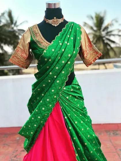 A green and pink half saree with a gold embroidered blouse.