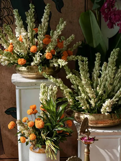 The beautiful contrast of white tuberoses and orange marigolds, arranged artfully in traditional vessels.