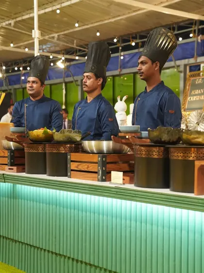 Our chefs in smart blue uniforms, manning the Asian cuisine station. This image showcases the specialized teams we have for different types of global cuisine.