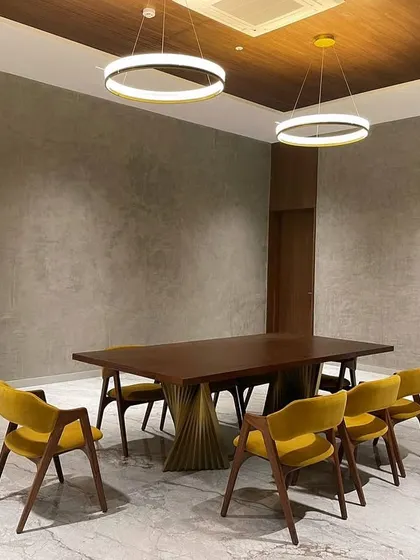 Custom furniture delivered to a site in Tiripur. This dining room features our table with a sculptural twisted metal base and chairs upholstered in a vibrant mustard yellow velvet.
