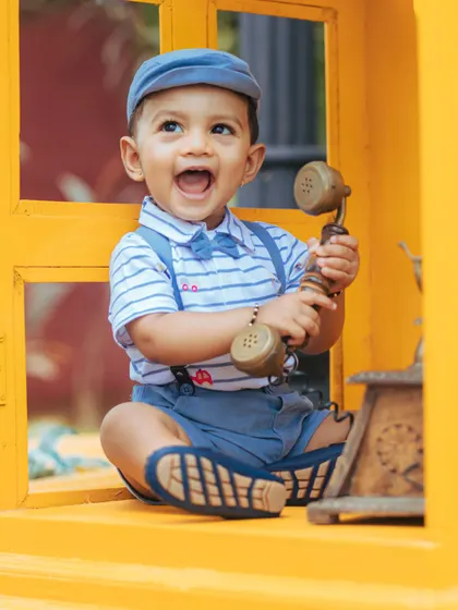 A duplicate of image 66, this vibrant shot captures a boy's happy expression in a yellow window frame with a telephone prop.