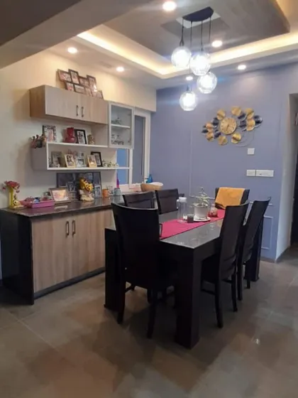 A dining area designed for family life, featuring a dark wood table and a custom crockery unit with open and closed storage. The pendant lights add a modern, warm glow to the space.