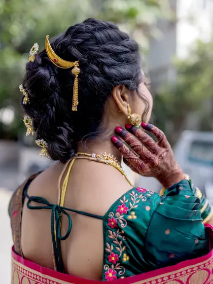A detailed shot of the back of the bride's blouse and her intricate hairstyle, adorned with traditional hair jewelry.
