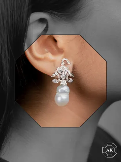 These paisley-style English earrings are crafted in 18K gold, featuring a stunning baroque South Sea pearl drop enhanced by natural round diamonds.