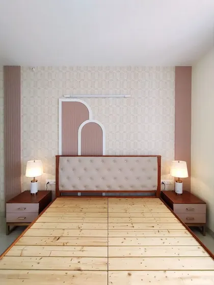 The symmetrical setup of the bed with matching bedside tables and lamps, creating a balanced and harmonious look. The wall paneling behind the bed adds texture and architectural interest.