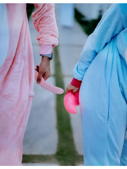 A playful detail shot of the couple holding the tails of their animal onesies, a cute and quirky pre-wedding photo idea.