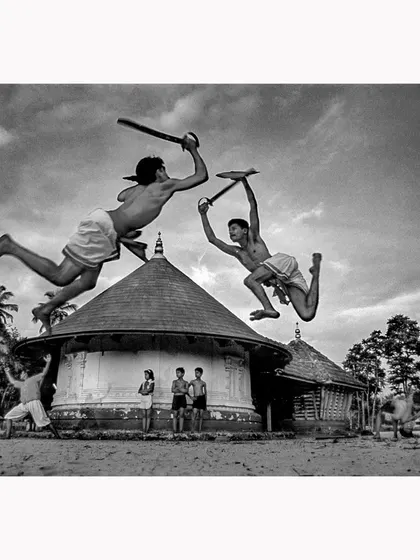 This is a moment of peak action from a Kalaripayattu practice in Kerala. I captured these two warriors mid-air to freeze the raw power and grace of this ancient martial art. This black and white fine art print emphasizes the dramatic form and timeless nature of their discipline.