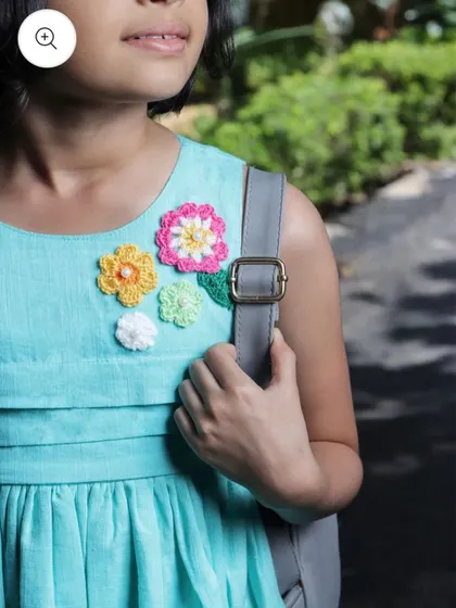 Here you can see a close-up of my custom floral patches on a child's dress. I create these appliqués in various colors and sizes, perfect for adding a playful and personalized touch to kids' clothing.