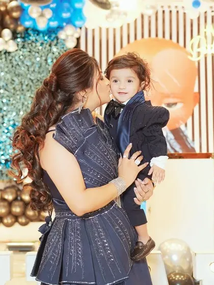 A mother's love captured in a single frame. This sweet, unposed photo shows a mother giving her son a kiss during his birthday celebration, a memory to cherish forever.