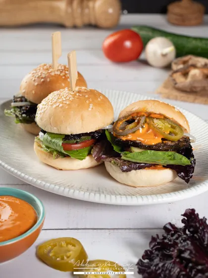 These mini burgers, or sliders, are arranged to look like a perfect appetizer for sharing. The bright, airy lighting gives the scene a fresh, daytime cafe feel.
