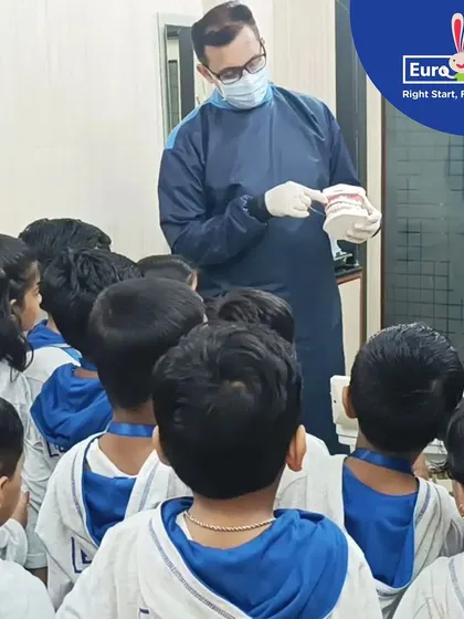 A dentist demonstrates proper brushing techniques on a model of teeth. Our field trips to local professionals help demystify experiences and teach children important healthy habits in an engaging way.