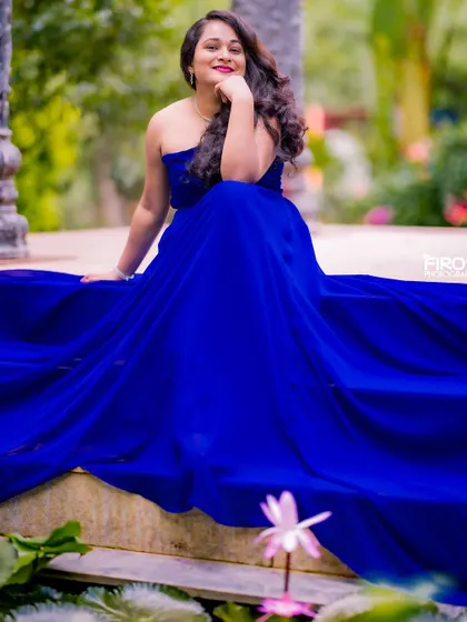 A beautiful solo portrait of the bride-to-be. She is seated by the water, her royal blue gown spread around her, creating a serene and elegant image that highlights her beauty.