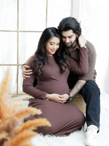 A modern and stylish couple's portrait. The earthy tones of their outfits complement the boho studio decor, creating a warm and inviting image.