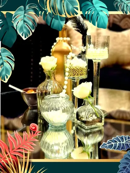 A close-up of a glamorous black and gold centerpiece, featuring white roses, pearls, and feathers for a touch of Art Deco style.
