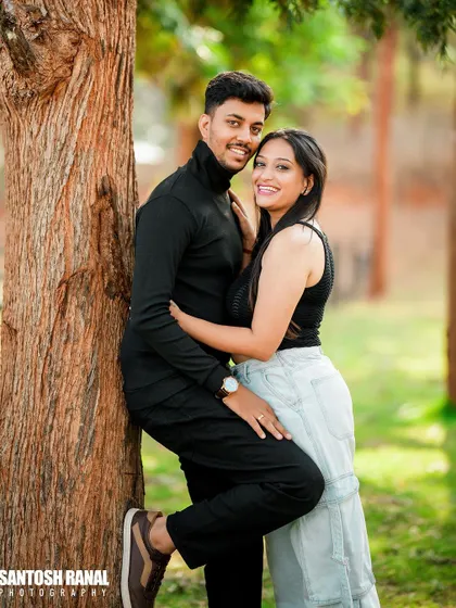 A stylish and confident portrait of a couple posing against a tree.