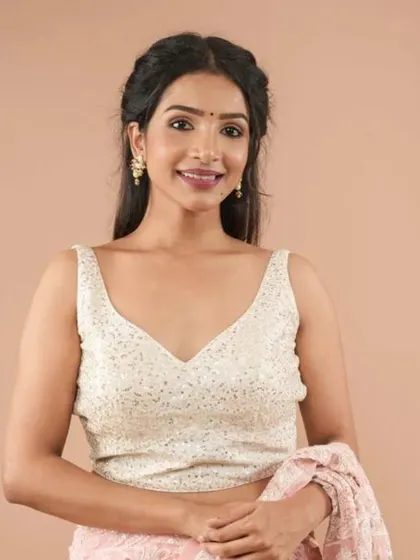 This sleeveless V-neck blouse is covered in shimmering white sequins, making it a dazzling choice for any celebration.