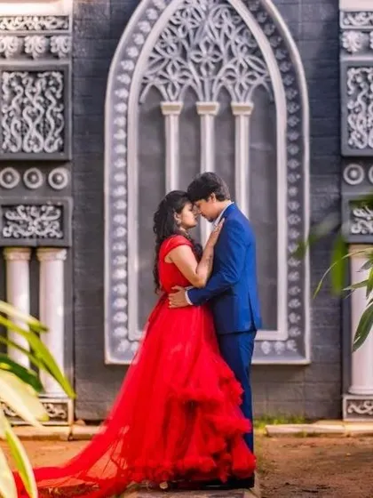A romantic embrace in front of an ornate building. The client's red ruffled gown creates a passionate and vibrant focal point.
