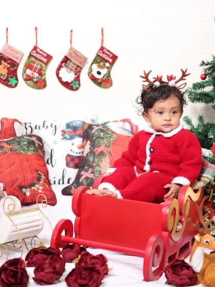 This Christmas setup features a cozy couch with festive pillows, stockings, and a tree, creating a complete holiday living room scene for the photoshoot.