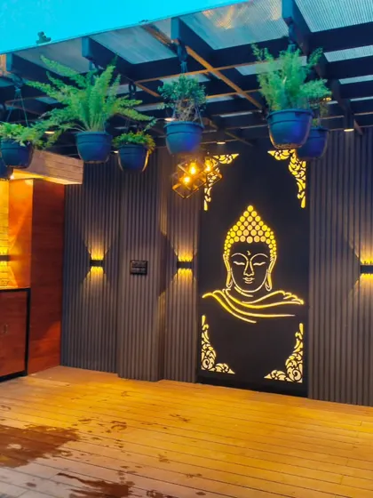 A beautiful backlit Buddha art panel on a slatted wall, part of a covered seating area in our Uttam Nagar project.