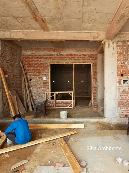 The interior of a project during the carpentry phase. Here, craftsmen are preparing wooden frames for doors and windows, a crucial step in defining the internal spaces of the home.