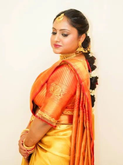 This side view highlights the elegant hair and makeup. The traditional braid and flowers are a key part of the South Indian bridal look, paired with flawless skin and eye makeup.