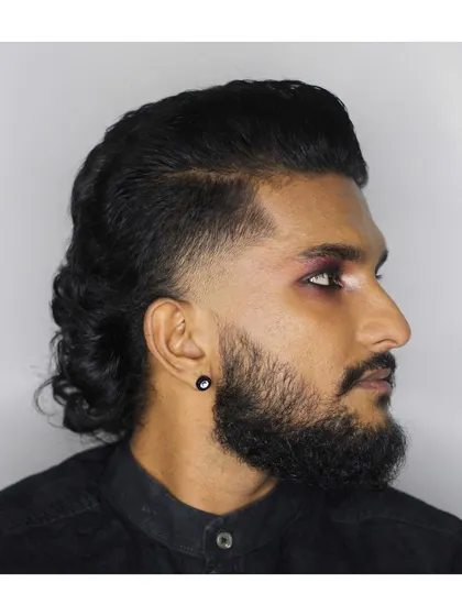 A modern mullet with a temple fade and a full beard. This look is all about sharp lines and contrasting lengths.