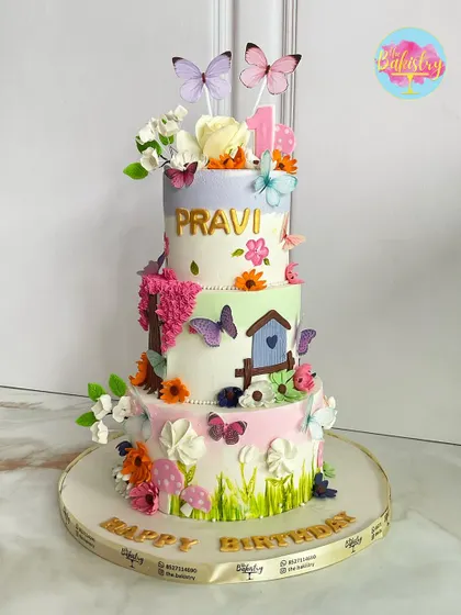 This three-tiered butterfly garden cake for Pravi's birthday is a burst of color and joy, featuring a birdhouse, bright pink trees, and dozens of handcrafted butterflies.