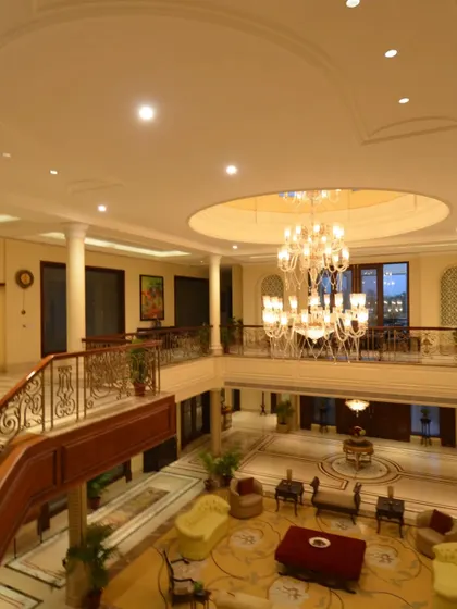 Another view of the grand, neo-classical lobby, looking down from the mezzanine level. The circular ceiling cutout and massive chandelier serve as the central organizing element of the space.