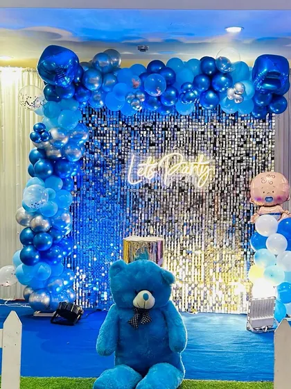 A simple yet fun "Let's Party" setup for a boy's birthday. The decor includes a blue color scheme, a teddy bear, and a baby boy foil balloon.