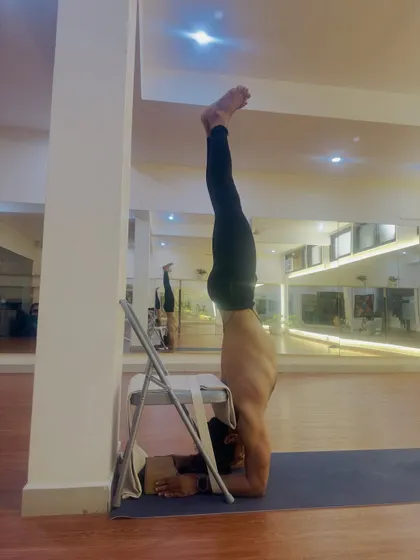 Using a chair and strap to refine the alignment in Pincha Mayurasana, the forearm stand. Even in self-practice, props are valuable tools to work on precision and stability.