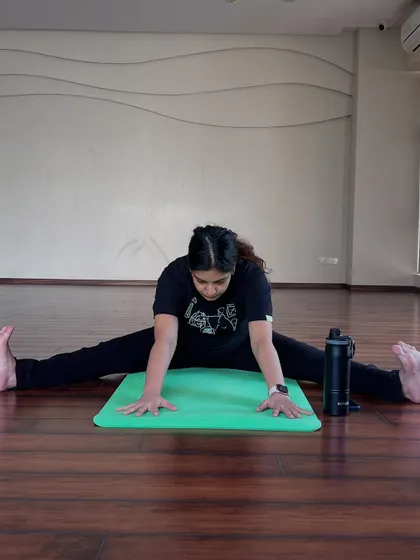 Here, a mother-to-be works on a wide-legged forward bend, or Upavistha Konasana. This pose is invaluable for increasing flexibility in the hips and preparing the body for childbirth.