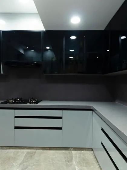 A modern kitchen with a striking contrast between matte grey lower cabinets and glossy black upper cabinets. The design is clean, minimalist, and highly functional.
