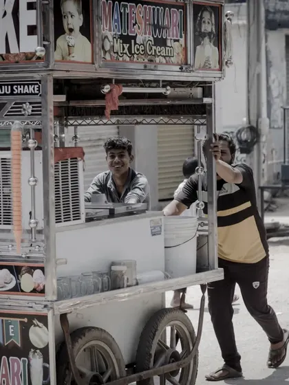 Two men pushing their food cart. This shot captures the physical effort and teamwork involved in street vending.