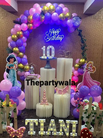 A beautiful princess theme for a 10th birthday, featuring a purple and pink balloon arch and light-up letters for the name.