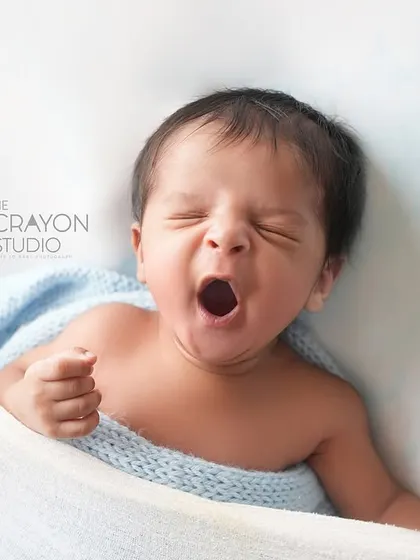 The biggest, most satisfying yawn from a tiny baby, captured while nestled in a soft hammock. A simple, authentic moment of newborn life.