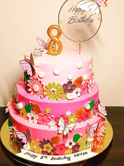 A magnificent three-tiered floral and butterfly cake in shades of pink for an 8th birthday.