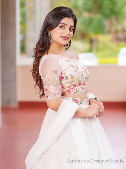 A close-up of a model in an elegant white lehenga with a one-shoulder blouse featuring delicate floral embroidery.