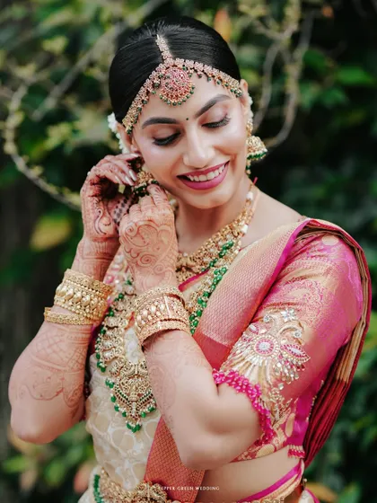 A beautiful bridal portrait showing the final touches being made to her earrings, a moment of quiet preparation.