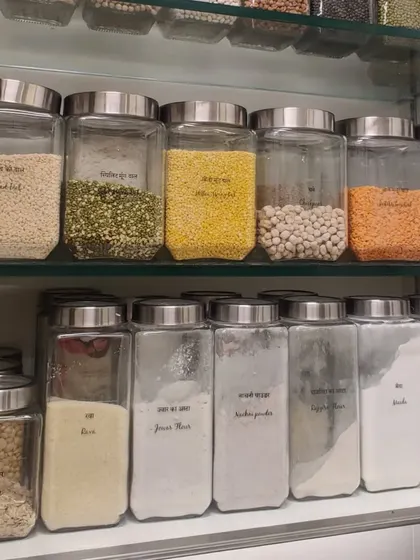 A pantry cabinet showcasing decanted flours and grains in labeled glass jars. This system not only looks great but also helps in keeping track of inventory and maintaining freshness.