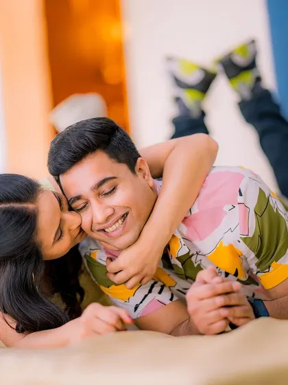 A playful and affectionate indoor moment. This candid shot is full of laughter and joy, capturing the fun side of the couple's relationship.