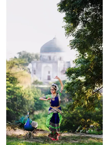 A Bharatanatyam dancer performs outdoors, with a historic tomb in the background and a peacock observing nearby. This demonstrates my work in artistic performance photography, blending cultural art forms with natural and architectural beauty.