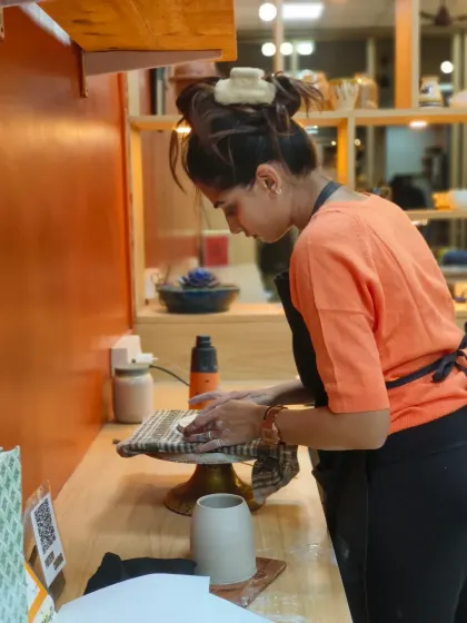 A student works on finishing her piece at a workstation. We teach all the steps that come after throwing, including trimming and surface decoration.