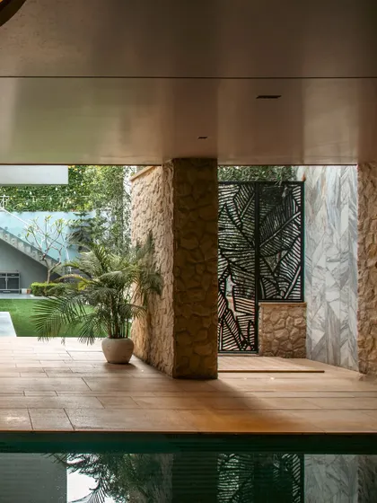 This outhouse features a stunning basement-level pool and lounge area. We used textured stone walls, decorative metal screens, and indoor planters to create an immersive and luxurious retreat that feels like a hidden world of its own.