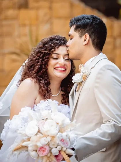 A sweet kiss for the bride. This curly-haired beauty looks absolutely radiant and happy in this tender moment.