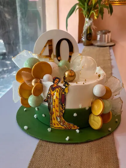A special cake designed for a tarot card reader's 40th birthday. The design incorporates an illustration of a tarot card and is decorated with gold and green spheres that give it a mystical, magical feel.