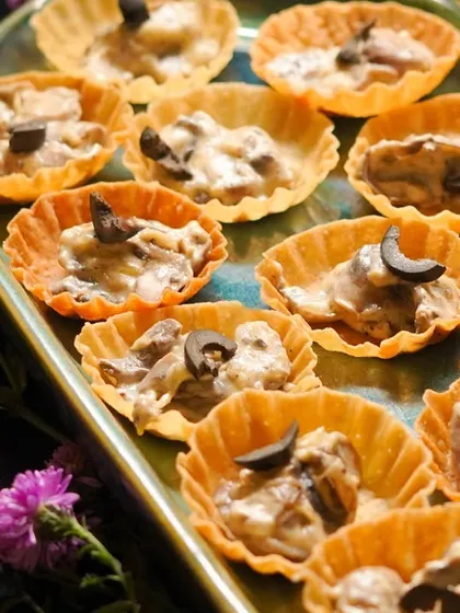 A closer look at the Creamy Mushroom Tarts, topped with black olives and served on a beautiful platter.